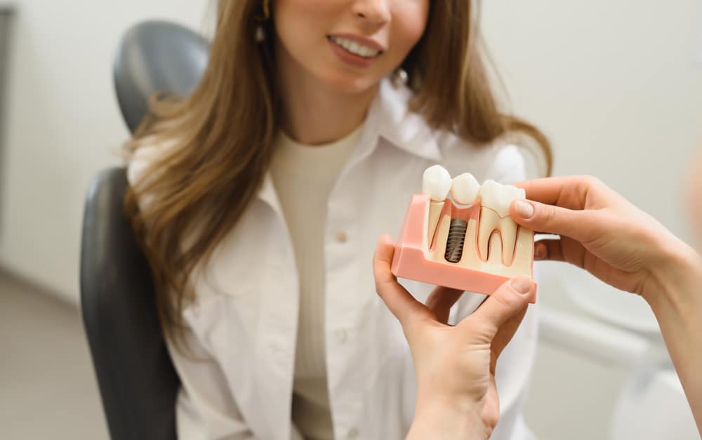 Doctor holding model of dental implant and explaining to patient how it works